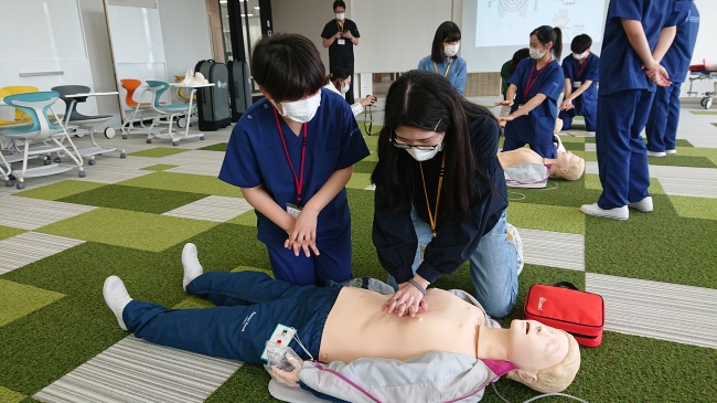 「手を揃えて押してください」専門学校生に指導を受ける本学学生